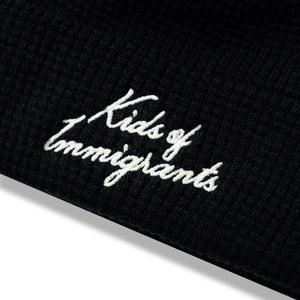 Kids Of Immigrants beanie in black with white script font